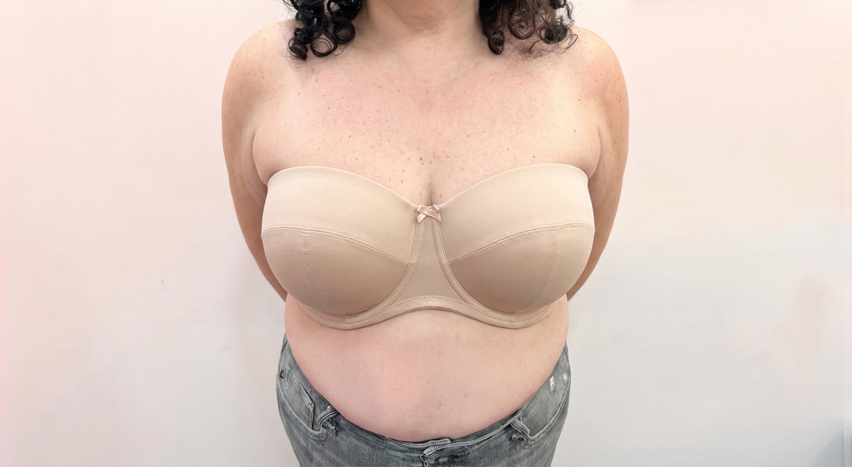 A person wearing a beige strapless underwire bra, shown from the shoulders to the hips against a plain light background.